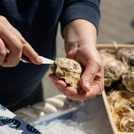 Personne ouvrant des huîtres fraîches, expérience culinaire locale et de qualité proposée par Solal Events