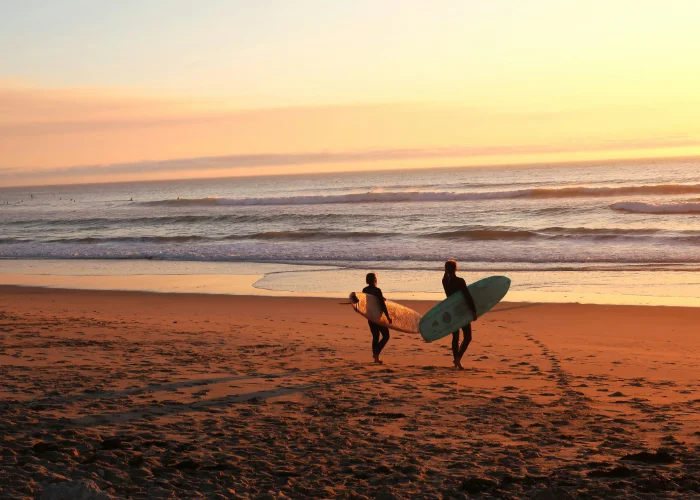 Surfeurs au coucher de soleil sur une plage portugaise – plus de 300 jours de soleil par an, idéal pour événements team-building