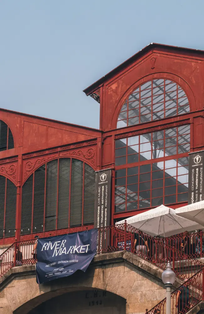 Bâtiment de marché couvert au Portugal avec façade rouge et bannière “River Market”, illustrant les lieux authentiques que Solal Events peut intégrer à vos parcours événementiels.