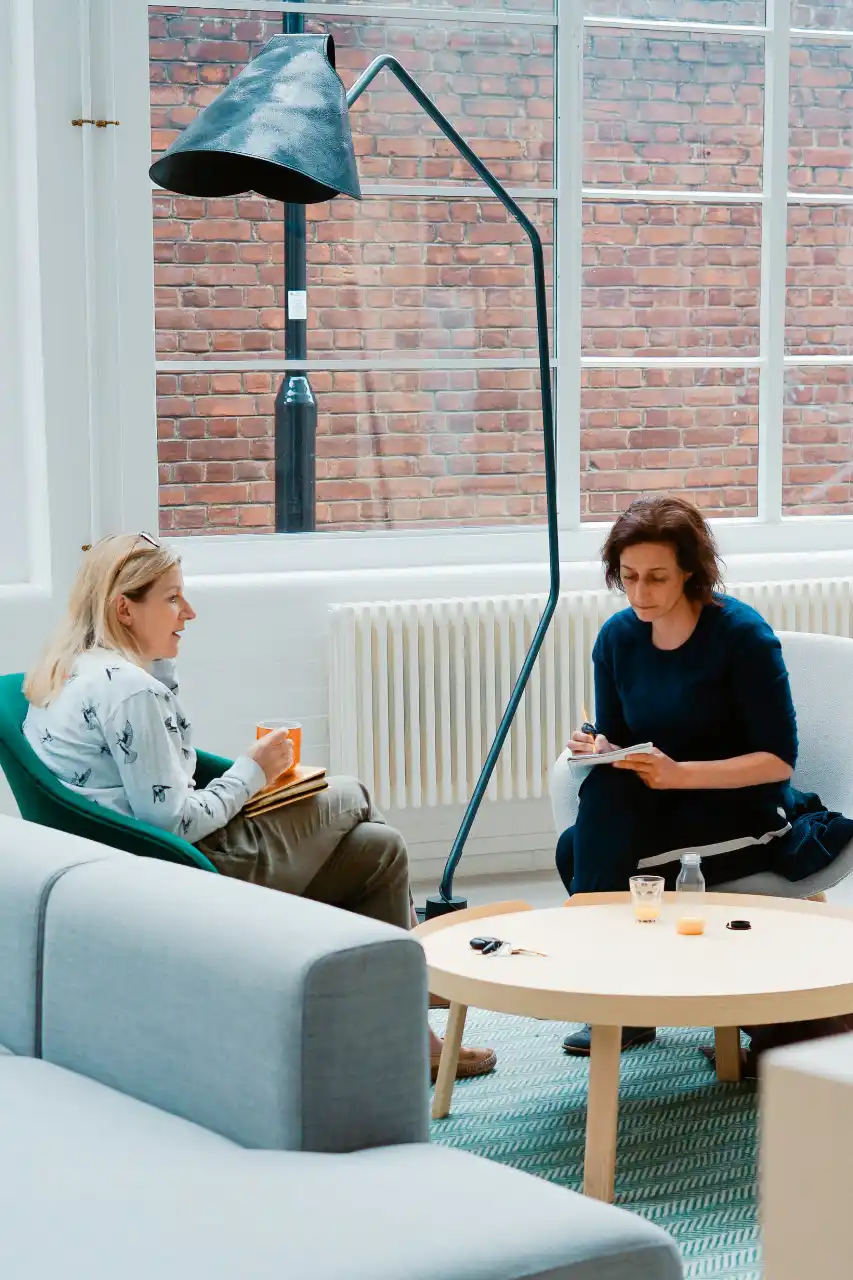 Deux femmes en pleine discussion et travail dans un espace open space lumineux, illustrant la rigueur, la discrétion et l’élégance des services MICE offerts par Solal Events en Algarve et partout au Portugal.